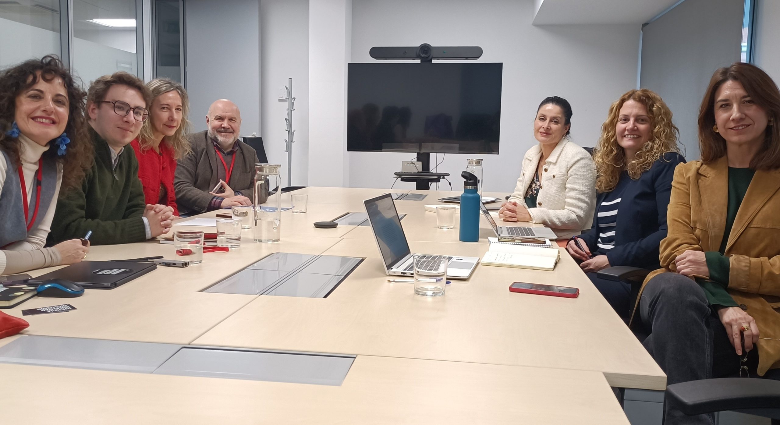 Siete personas integradas por el equipo de la AINODI y de la Plataforma Padrón por Derecho están sentados mirando a la cámara alrededor de una mesa en una sala de reuniones