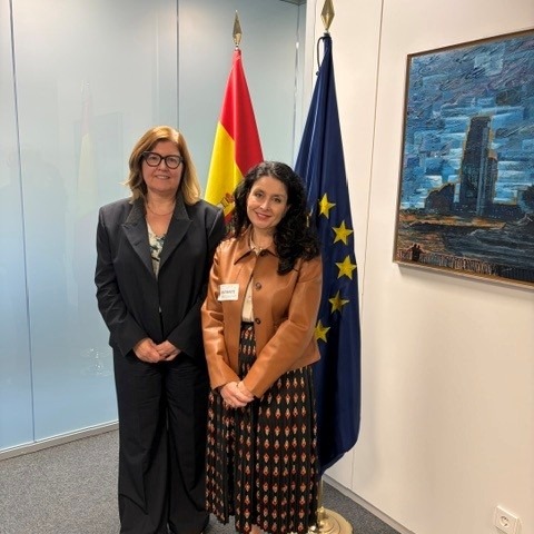 Las presidentas de la AINODI y del INE de pie delante de las banderas de la UE y España