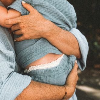 Bebé en brazos de un adulto. Ambos visten de azul y no se ven las caras