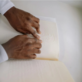 Manos de un hombre leyendo un libro en braille